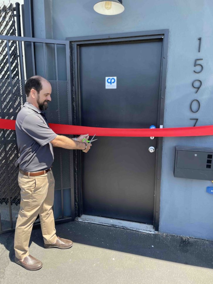 Ian McKelvy of CP Communications is pictured at the front door cutting the ribbon at the main entrance of the company’s new L.A. office.