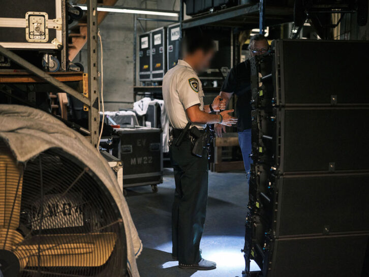 A police officer in the warehouse of Se7ven Sounds Music, Inc aids the confiscation of counterfeit L-Acoustics loudspeakers. Photo: Zack Wittman / L-Acoustics.