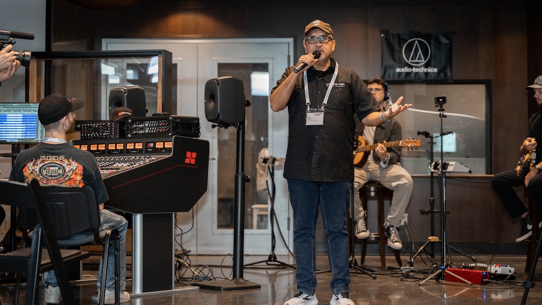 SSL’s Rick Naqvi addresses the audience prior to a live, simultaneous, three-console tracking session—SSL Origin evo, SSL Oracle and Harrison 32Classic—using Audio-Technica 40 and 50 Series mics at the source and Genelec Ones smart active monitors at each of the three setups. Photo: Future/Kevin Craig