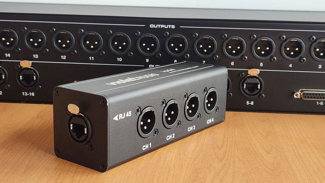 The Violet Audio io44 four-channel XLR-to-Ethercon adapter (foreground) and the DX16B 16-channel passive audio splitter.
