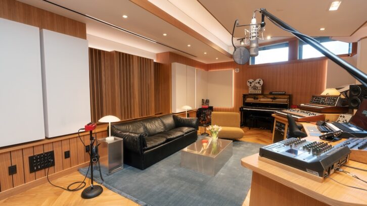 Inside SongBoy Studios, the walls are clad in oak wood paneling, herringbone timber flooring runs throughout, and a custom-built desk serves as the centerpiece of the control room.