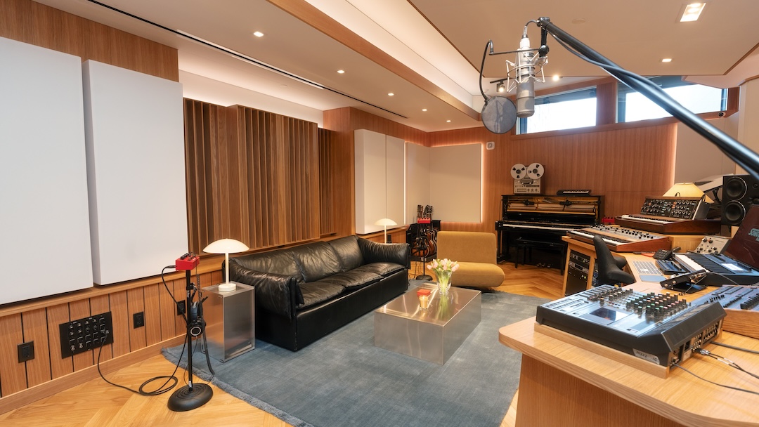Inside SongBoy Studios, the walls are clad in oak wood paneling, herringbone timber flooring runs throughout, and a custom-built desk serves as the centerpiece of the control room. 