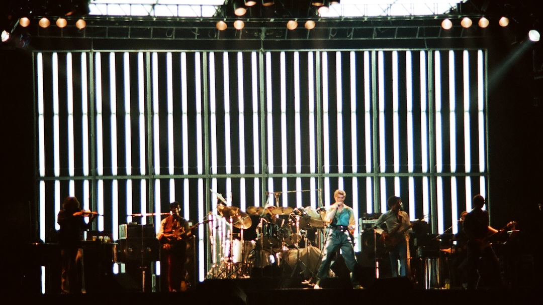 David Bowie performs on stage at Earls Court Arena on August 28th, 1978 in London, England. (L-R) Simon House, Carlos Alomar, Dennis Davis, David Bowie, George Murray and Adrian Belew. Photo: Pete Still/Redferns/Getty Images.